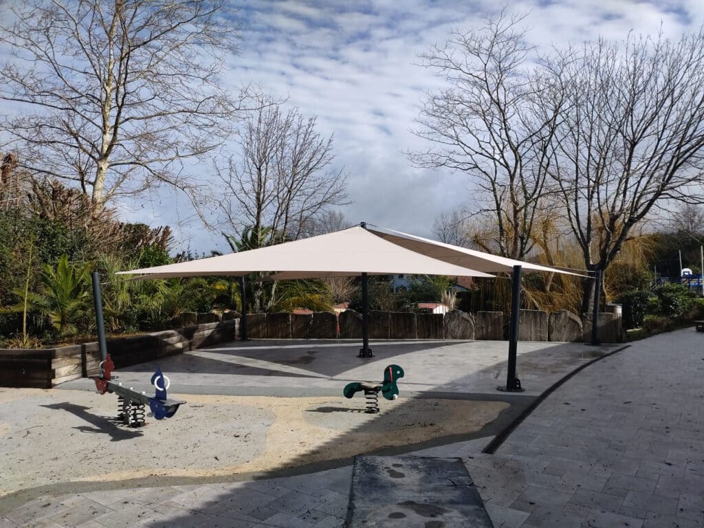 Ambiance ombragée sous des voiles d’ombrage triangulaires couleur beige sablé sur une terrasse